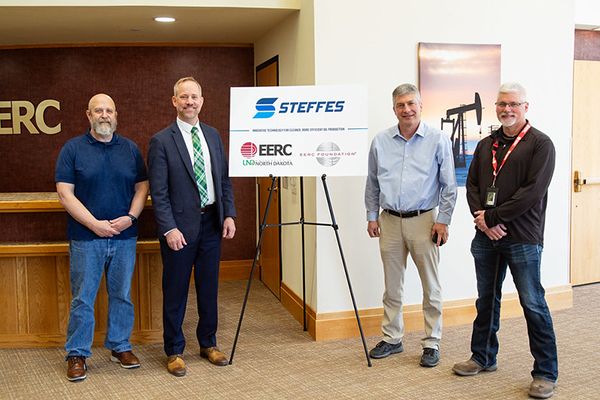 4 men pose for a photo around a poster with Steffes, EERC, and EERC Foundation logos on it.